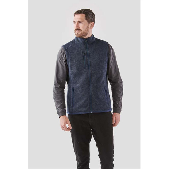 A man models a navy blue fleece vest with a full zip, featuring a logo and side pockets.