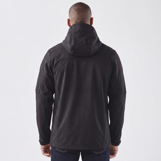 A black softshell jacket with a hood, featuring a logo, shown from the back on a model.