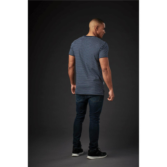 A man wearing a navy and white striped crew neck tee, paired with dark jeans, viewed from the back against a dark background.