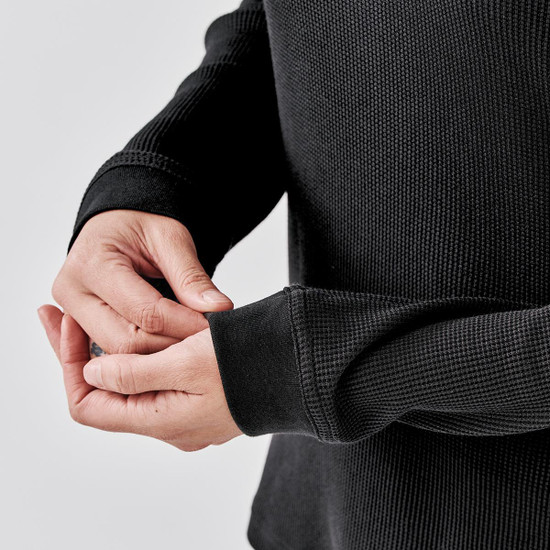 A black crew neck shirt with textured fabric, featuring fitted sleeves and a snug fit around the wrists.