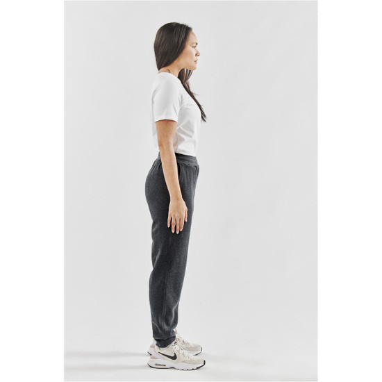 A pair of women's grey fleece joggers displayed on a model, alongside a plain white t-shirt and sporty shoes.