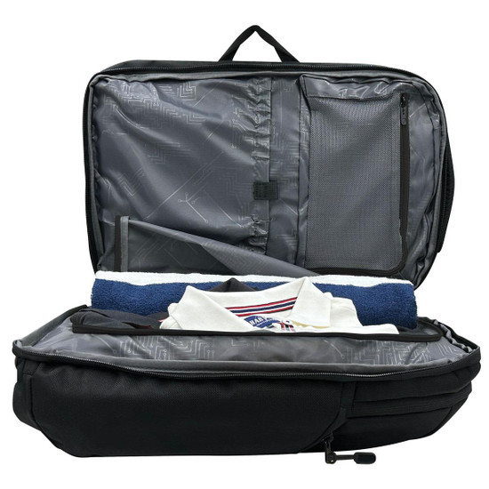 A black backpack with an open interior, featuring grey lining and neatly arranged items including a towel and a shirt.