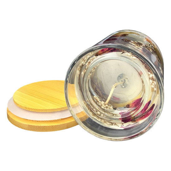 A floral candle with dried flowers encased in clear wax, featuring a bamboo lid.