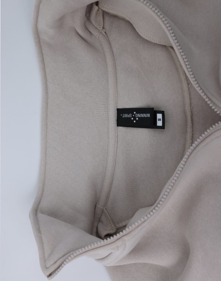 A light beige 1/2 zip collar polar fleece jumper with an inner view showcasing its soft fabric and a label.