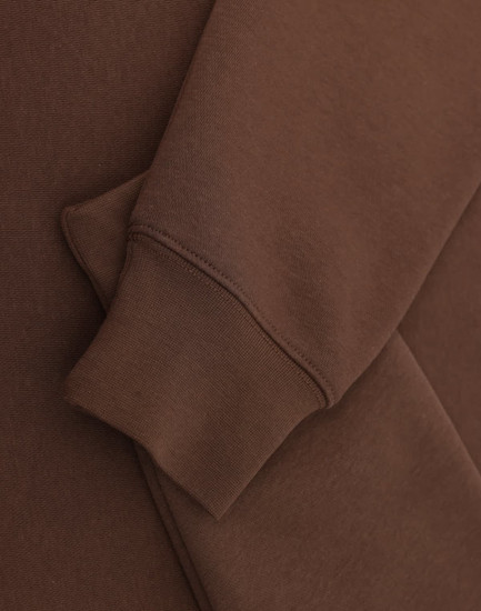 A brown 1/2 zip collar fleecy sweat featuring a smooth fabric and a cuffed sleeve. Includes branding.