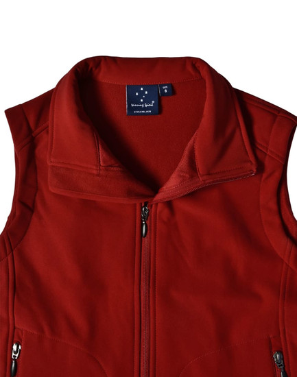 A red softshell vest with a high collar and a logo on the inside label. Features zippered pockets.
