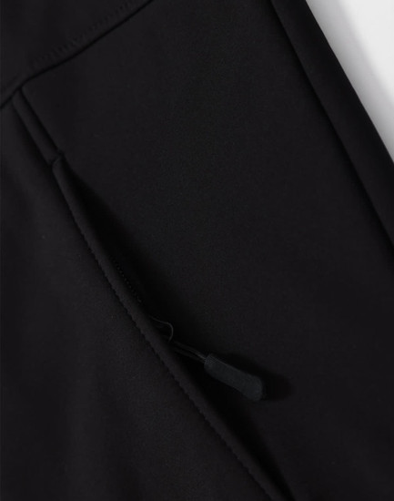 A close-up of a black softshell hoodie with a zippered side pocket and a logo.