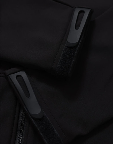 Close-up of a black softshell jacket featuring zippers and velcro details. The jacket has a logo on it.