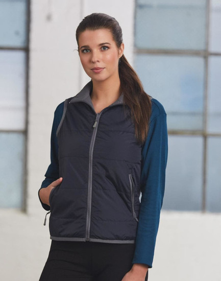 A woman models a navy blue versatile vest with grey accents over a long-sleeve top, featuring pockets and a zip.