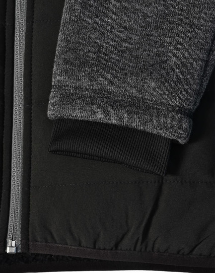 A black quilted jacket featuring heather grey sleeves and a ribbed cuff, with a side zipper and fabric texture detail.