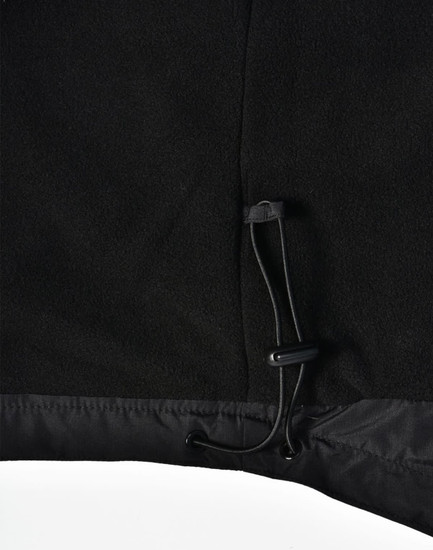 A close-up of a black unisex jacket featuring a pull cord at the hem, with a soft textured finish.