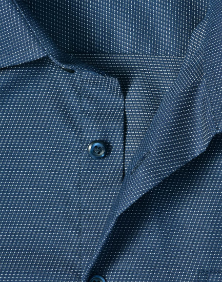A close-up of a navy blue men's button-up shirt featuring a pin dot pattern and blue buttons.