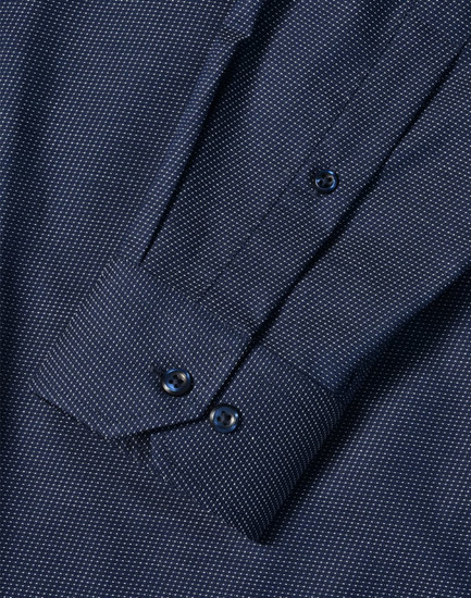 A men's long sleeve button-up shirt in navy with a pin dot pattern and cuff details. Features a logo.