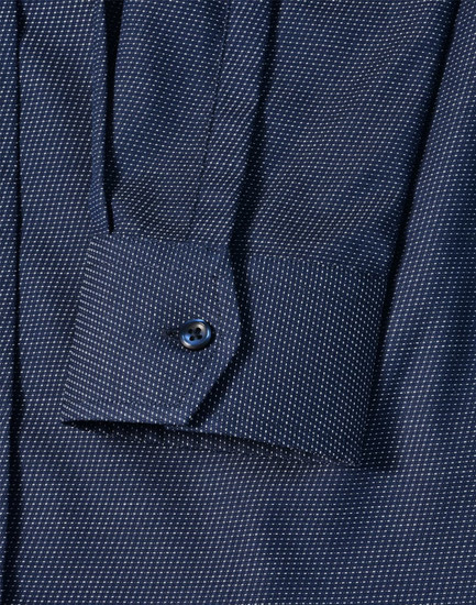 A navy blue pin dot stretch long sleeve shirt with a buttoned cuff and a branded logo.