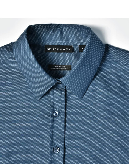 A blue pin dot stretch button-up shirt with a semi-fitted design and collar, featuring a logo tag.
