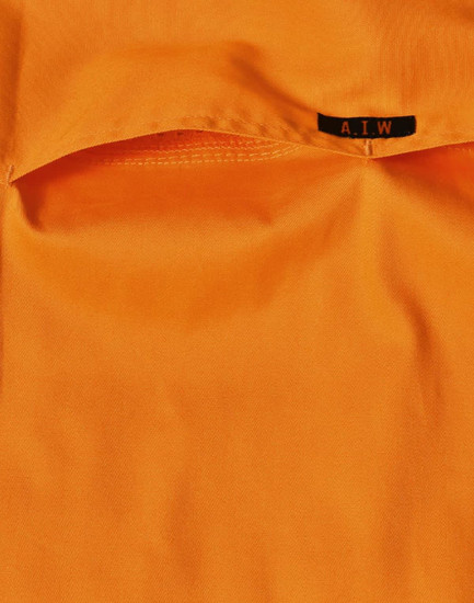 An orange work shirt featuring a pocket and a tag with a logo.