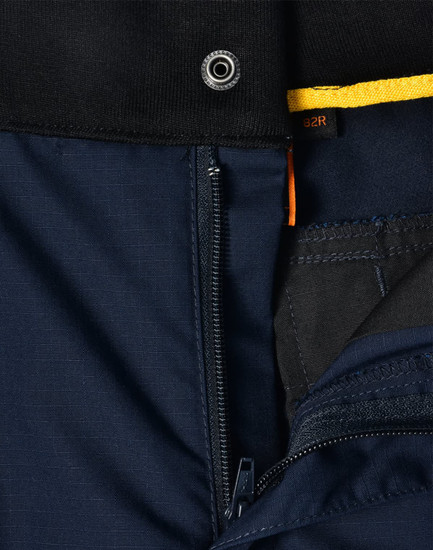 A close-up of navy Rip-Stop Poly/Cotton Stretch Work Pants, showcasing the zipper and fabric texture. Features a logo.