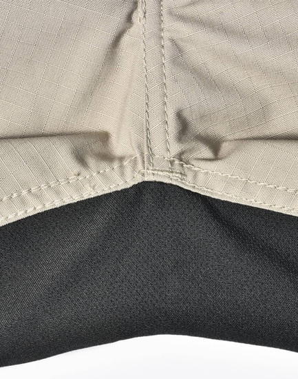 A close-up of Rip-Stop poly/cotton stretch work pants, featuring a beige upper section and a black lower section with stitching.