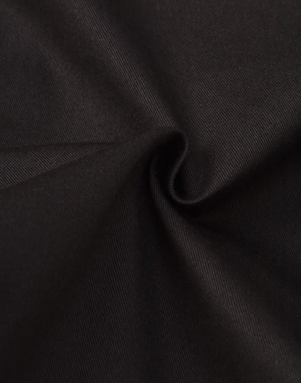 A close-up of black cotton fabric, showcasing a smooth texture and slight stretch. The material appears to be durable.