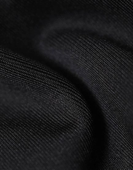 A close-up of a black softshell fabric, showcasing its smooth, textured surface. The material appears durable and flexible.