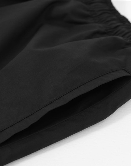 Unisex black mercerised cotton shorts featuring an elastic waistband and a smooth finish.
