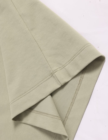 A close-up of a light green premium cotton T-shirt featuring short sleeves and neat stitching.