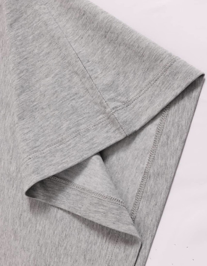 A close-up of a grey long-sleeve cotton tee shirt, featuring a stitched hem and smooth fabric texture.