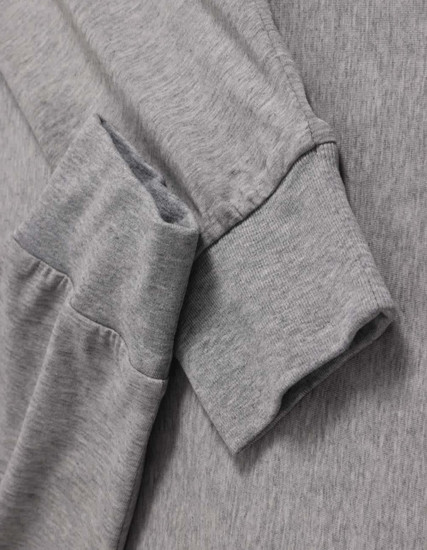 A grey long-sleeve tee shirt with a soft fabric and cuffed sleeves, featuring a logo on the side.