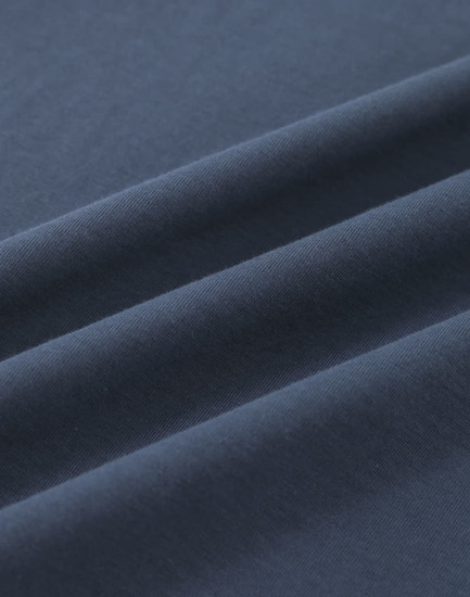 A close-up of soft, dark navy cotton fabric with smooth folds, showing its texture and quality.