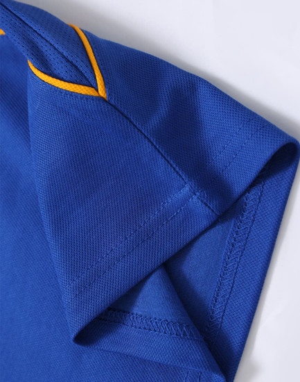 A close-up of a blue polo shirt featuring yellow stitching, showcasing the sleeve and collar detail.