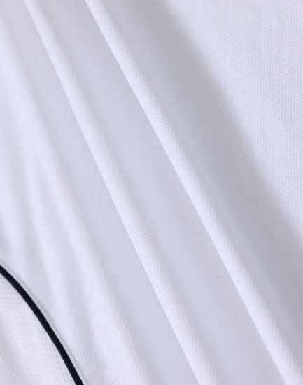 A white polo shirt with a textured fabric and contrasting detailing, featuring a logo.