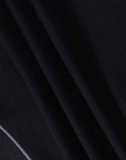 A close-up of textured black fabric, showcasing the material of a polo shirt. It has a logo detail.
