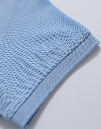 A light blue polo shirt with a textured finish, featuring a folded sleeve and a branding logo.