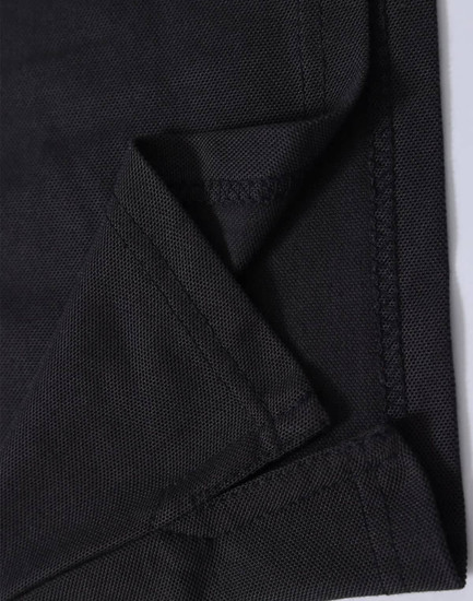 A close-up of black fabric showing the folded edge and stitching detail of a polo shirt. The fabric has a textured finish.