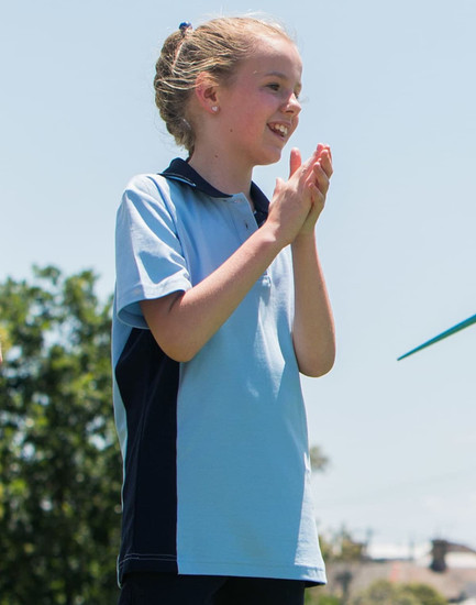 A light blue and navy polo shirt on a smiling child, with a logo on the chest.