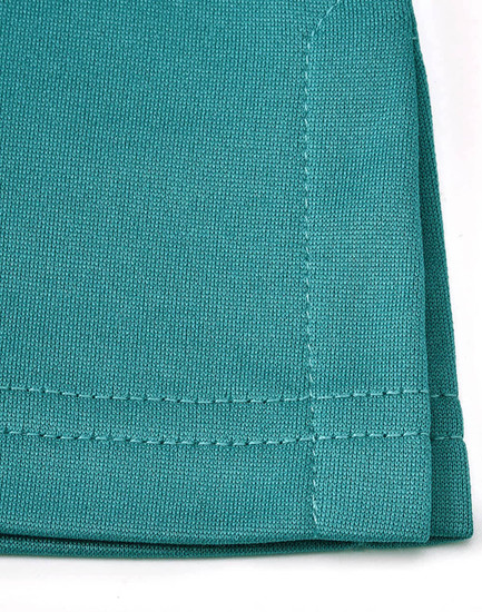 A close-up of a teal sustainable poly/cotton polo shirt showing the fabric texture and stitching details.