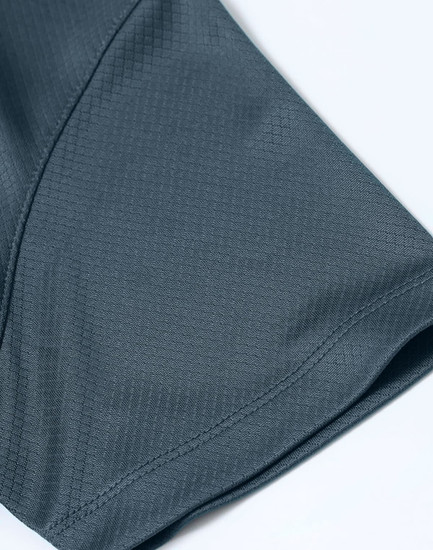 A close-up of a dark grey Jacquard knit fabric showing a textured pattern, part of a men's polo shirt.