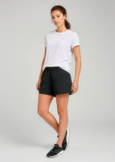 A woman models black sports shorts paired with a white t-shirt, standing against a neutral background.