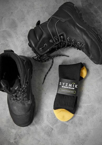 A pair of black work boots alongside a black and yellow sock with a logo.