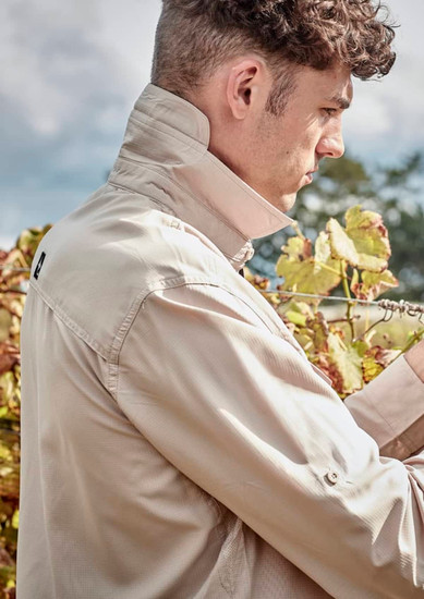 A light beige men's outdoor long sleeve button-up shirt, featuring a collared neck and a logo on the back.