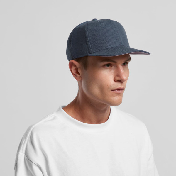 A blue cap with a structured design and a logo, worn by a model in a white t-shirt.
