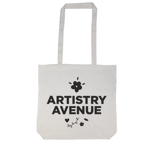A tote bag with a long handle featuring the text "ARTISTRY AVENUE" and decorative floral elements.