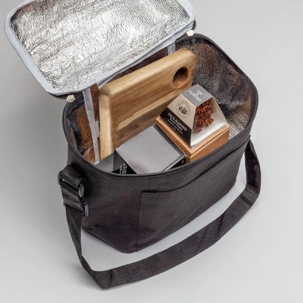 A cooler bag in black with a silver interior, containing a wooden board, snacks, and a bottle.