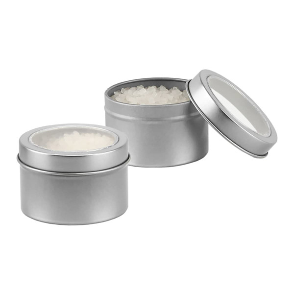 A silver tin containing bath salts, with one lid off to reveal the contents inside.