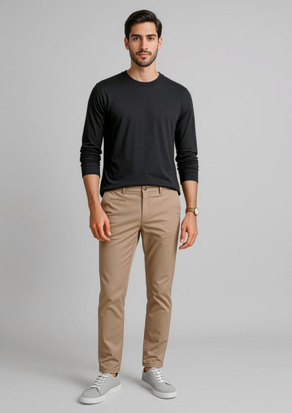 A pair of men's tapered stretch chino pants in beige, paired with a black long-sleeve shirt and white sneakers.