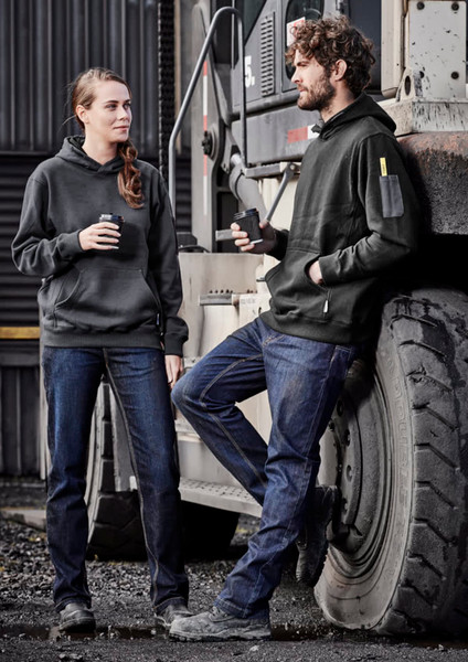 Two individuals wearing black hoodies and blue stretch denim work jeans, standing by a large vehicle.