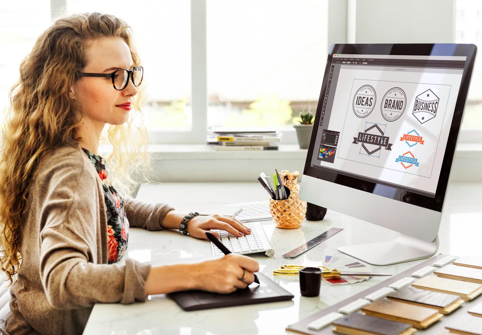 Designer editing logo artwork on screen, anchor points visible around the selected shape