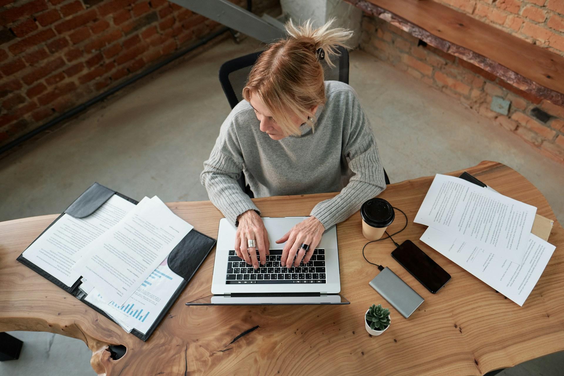 Small business owner working on a laptop surrounded by documents and branded stationery