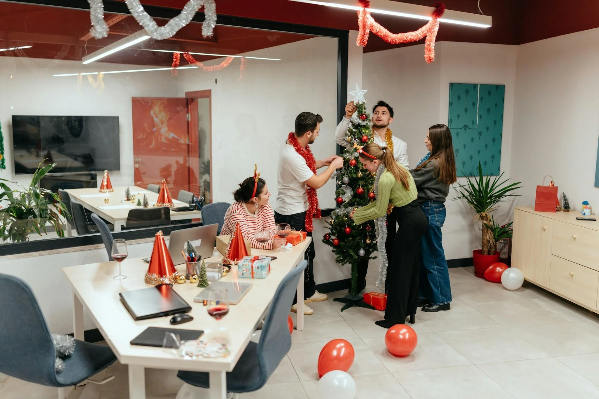 Office employees decorate a tree in a corporate office, ready and waiting for the perfect corporate christmas gifts