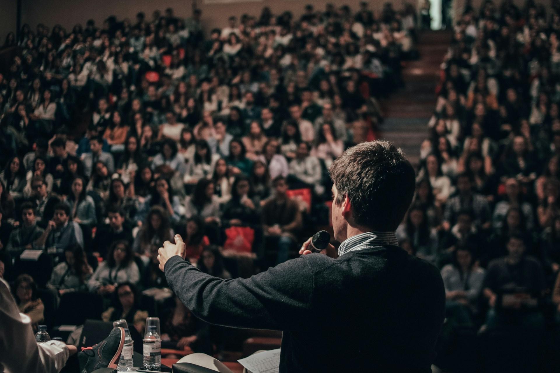 Keynote speaker addressing a large conference audience from the stage